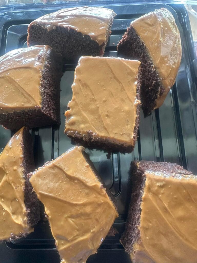 Chocolate cake slices with caramel frosting on top are displayed on a black tray in this image from Roatan, Honduras.