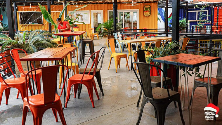 Al fresco seating with colorful chairs and tables at Macaw Container Market, a popular spot in Roata.