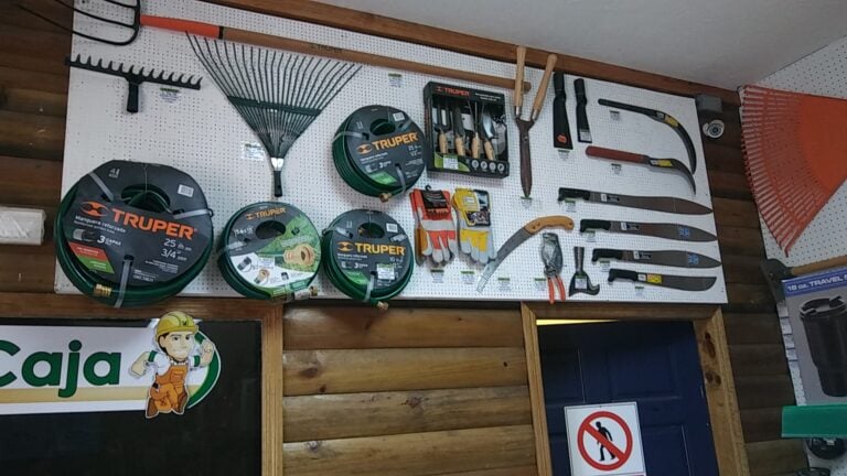 A display of gardening tools, hoses, and equipment on a pegboard inside a hardware store on Roatan, Bay Islands, Honduras.