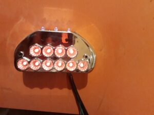 A close-up of a vape device with a colorful LED-lit coil against an orange background, part of a business listing on RoatanYP.com in Honduras.