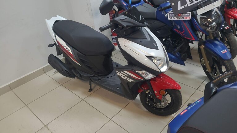 A black and red Yamaha scooter is displayed alongside blue and black motorcycles inside a showroom on Roatan, Bay Islands, Honduras.