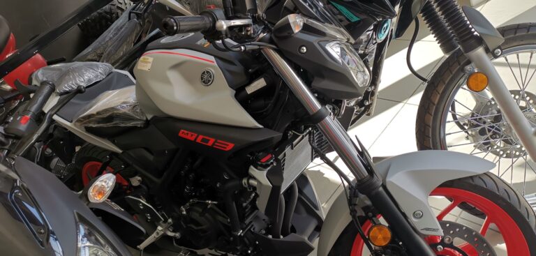 A close-up view of two Yamaha motorcycles parked indoors, with one displaying a white and black body with red accents, situated in a business on Roatan, Honduras.