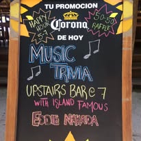 A chalkboard sign outside a bar in Roatan, Honduras advertises live music performances featuring Island Famous Eide Navarro with colorful text and musical notes.
