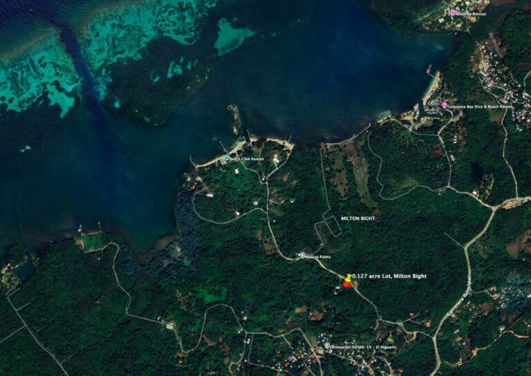 Aerial view of Roatan, Honduras, showing the coastline, lush green forested areas, and the turquoise waters of the Caribbean Sea with marked landmarks including Beach Club Roatan and Turquoise Bay Dive & Beach Resort.