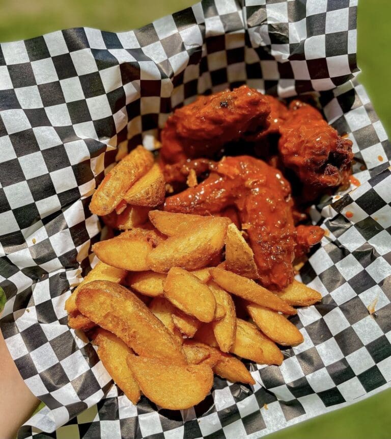 Saucy fried chicken with golden plantain slices served in a black-and-white checkered basket in Roatan, Honduras.