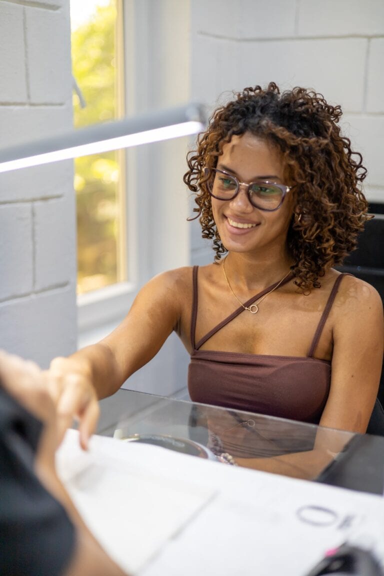 Woman smiling and shaking hands in an office setting.