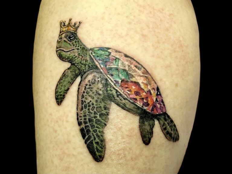 Colorful sea turtle tattoo with a small crown on a person's skin, reflecting Roatan, Honduras marine life.