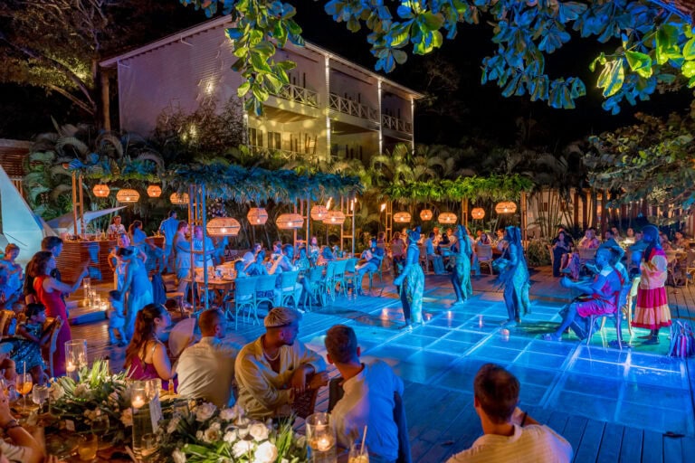 Nighttime outdoor party with dancing and colorful lighting in Roatan, Honduras.