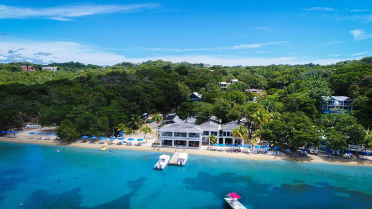 Beachfront view of Luna Beach Luxury Boutique Resort in Roatan, Honduras, with clear blue waters and.