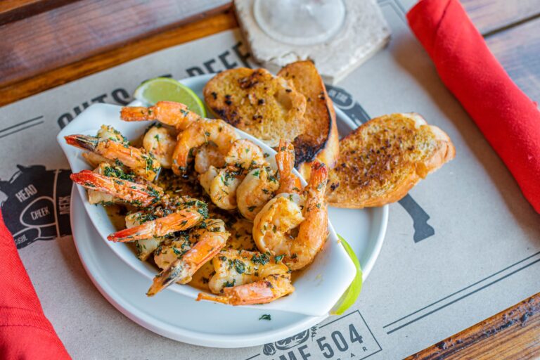 A seafood dish with shrimp, grilled bread, and lime slices served on a white plate at a restaurant in Roatan, Honduras.