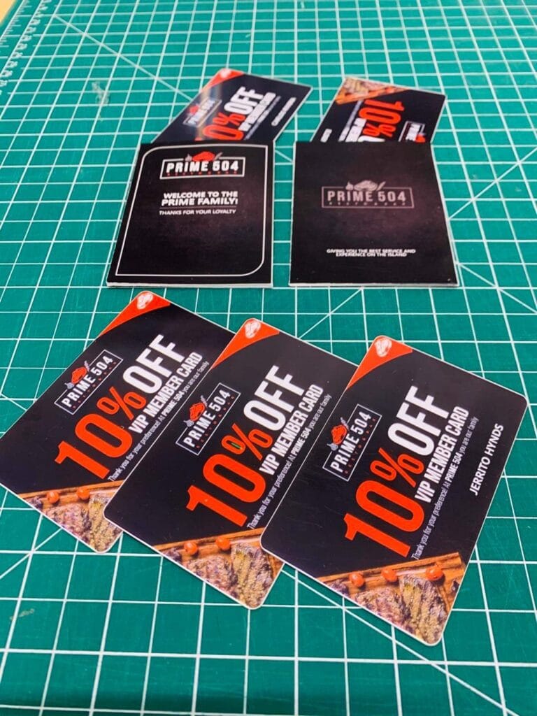 Multiple Prime 504 VIP membership discount cards are displayed on a green cutting mat, promoting loyalty benefits for businesses in Roatan, Honduras.