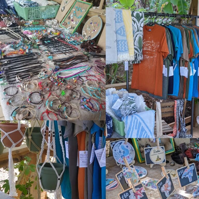 A display of colorful handmade jewelry, clothing, towels, and souvenirs at an outdoor market in Roatan, Honduras.