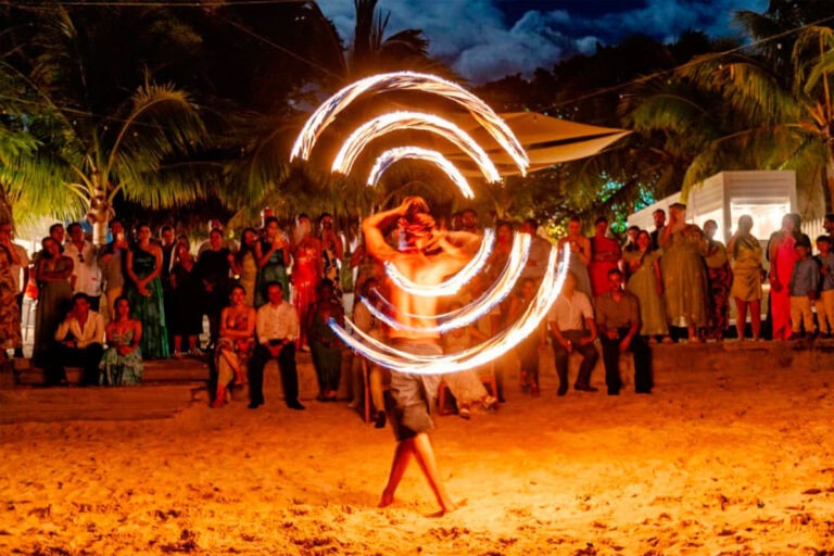 Nighttime fire dance show on Roatan island with performers and audience.