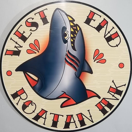 A circular emblem for a Roatan, Honduras business features a stylized blue shark with red and yellow accents, surrounded by decorative lettering and red dots.