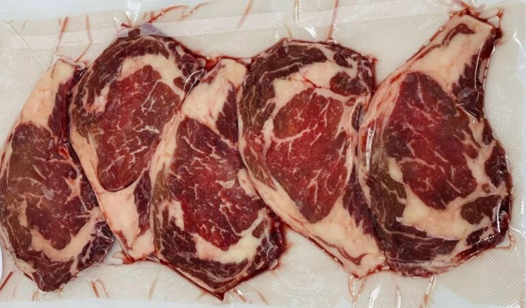 Four raw, marbled cut of beef are laid out on a butcher paper surface in this image from Roatan, Honduras.