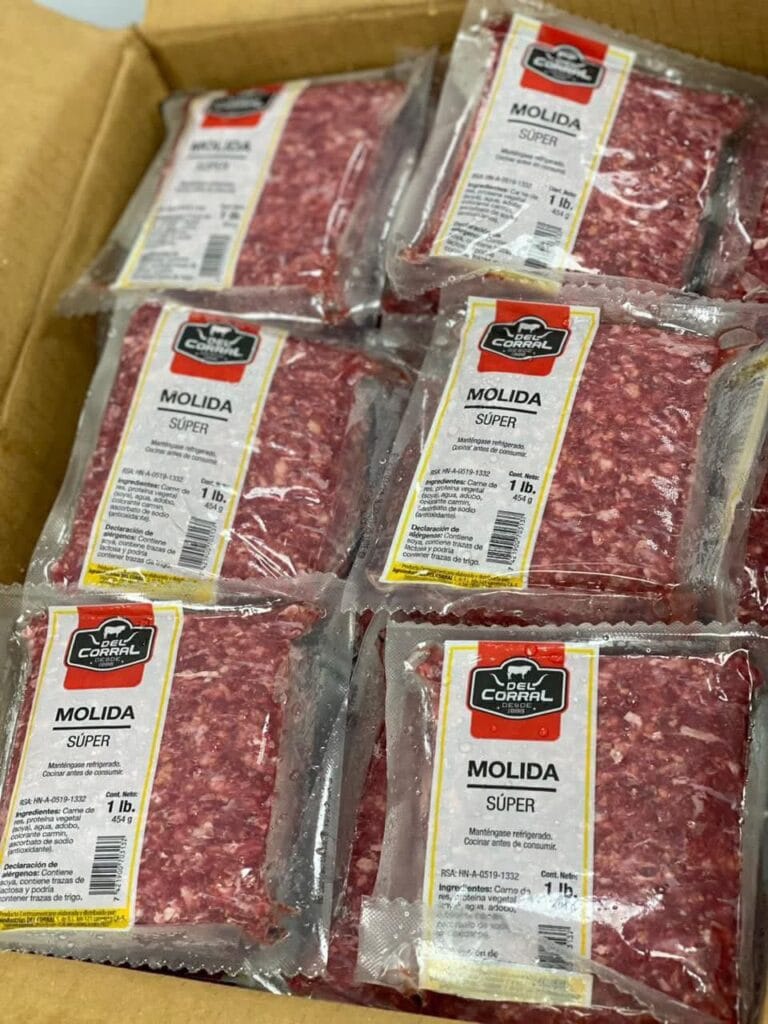 Packaged ground beef labeled "MOLIDA SUPER" displayed inside a cardboard box, with the packaging indicating it is from Del Corral in Roatan, Honduras.