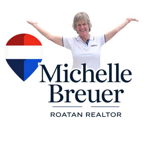 A smiling woman in a white polo shirt stands with arms outstretched next to a logo featuring a heart-shaped design with red, white, and blue sections and the text "Michelle Breuer Roatan Realtor" on a plain white background.