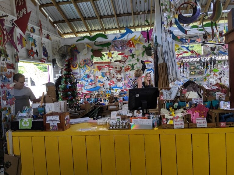 A colorful souvenir shop in Roatan, Honduras, displays hand-painted wooden animal decorations, including fish, crabs, and starfish, along with other local crafts and handcrafted items within a rustic wooden structure.