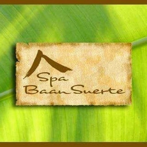 A parchment-style sign reading “Spa Baan Suerte” rests on a bright green tropical leaf in Roatan, Honduras.