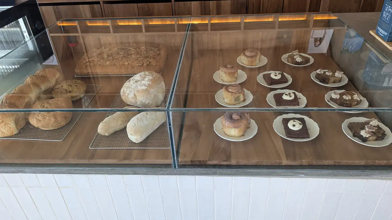 A glass display case showcasing a variety of baked goods including bread, pastries, and cakes inside a bakery on Roatan, Honduras.