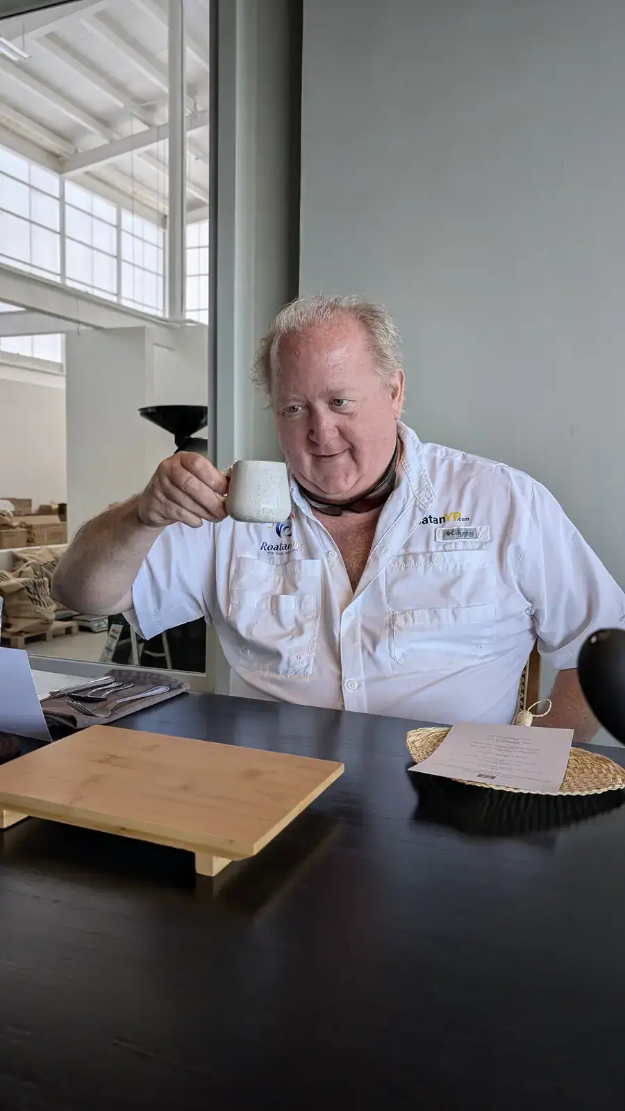 Jason Janes lifting a ceramic mug of Cup of Excellence coffee at Spirit Origin Coffee Omakase in Roatan, Honduras