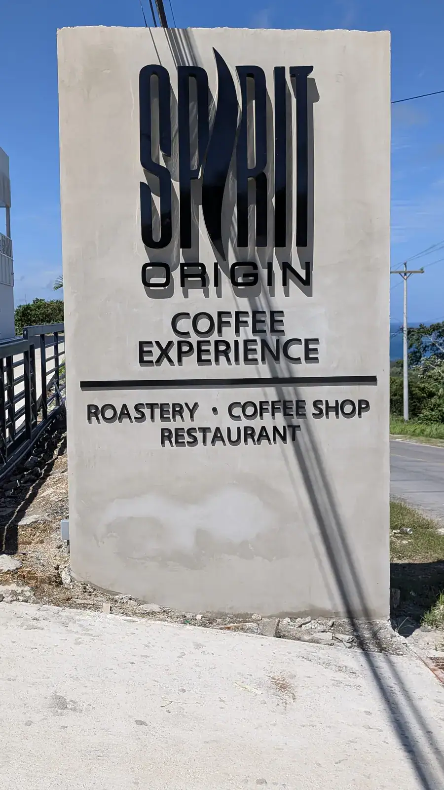 Spirit Origin Coffee Experience monument sign at the main road entrance in First Bight, Roatan, Honduras