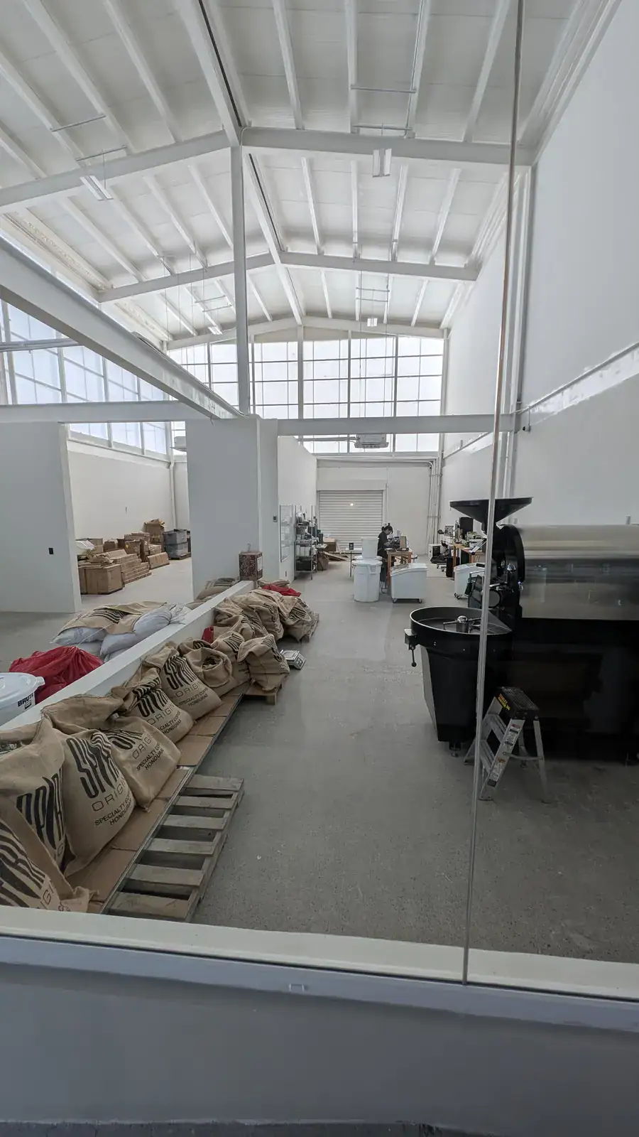 Spirit Origin Coffee on-site roastery with commercial drum roaster and burlap sacks of green coffee beans, Roatan, Honduras