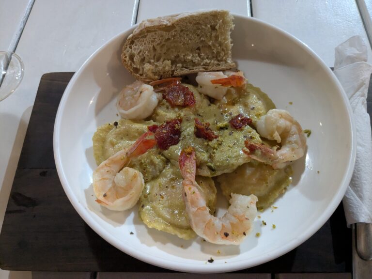 Shrimp and bacon served with mashed potatoes and bread on a white plate at a restaurant in Roatan, Honduras.