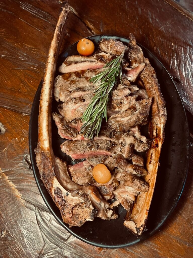 Delicious T-bone steak served with fresh herbs and vegetables at The Estancia Steak House, Roatan.