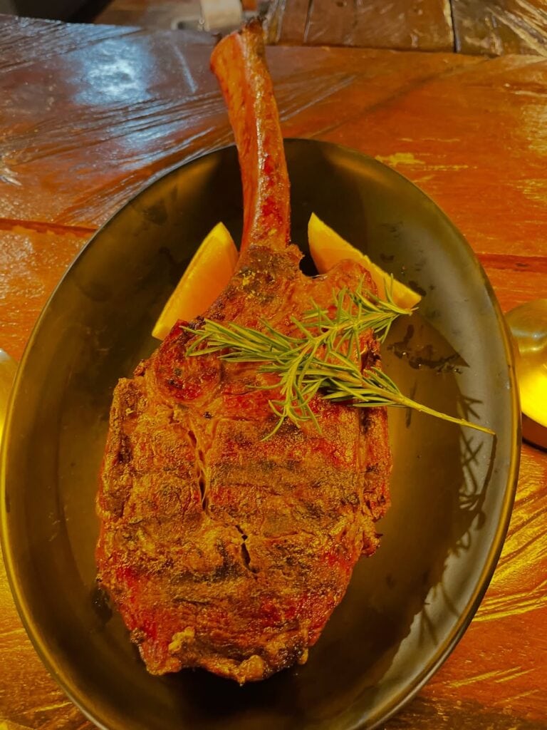 Delicious grilled ribeye steak served with lemon wedges and fresh herbs at The Estancia Steak House,.