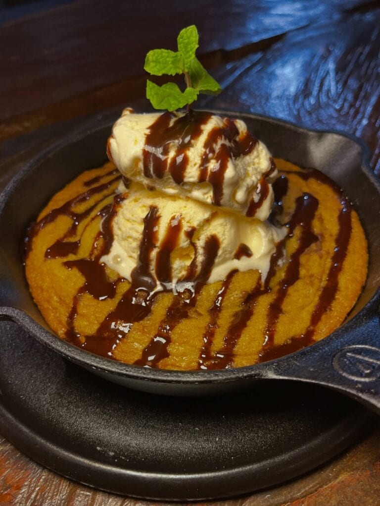 Delicious dessert featuring vanilla ice cream topped with chocolate sauce, served in a skillet. Perf.