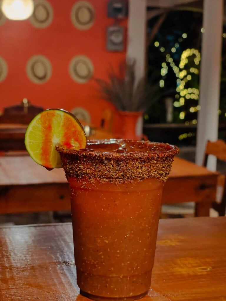A vibrant cocktail served at The Estancia Steak House, featuring a lime wedge garnish and a salted r.