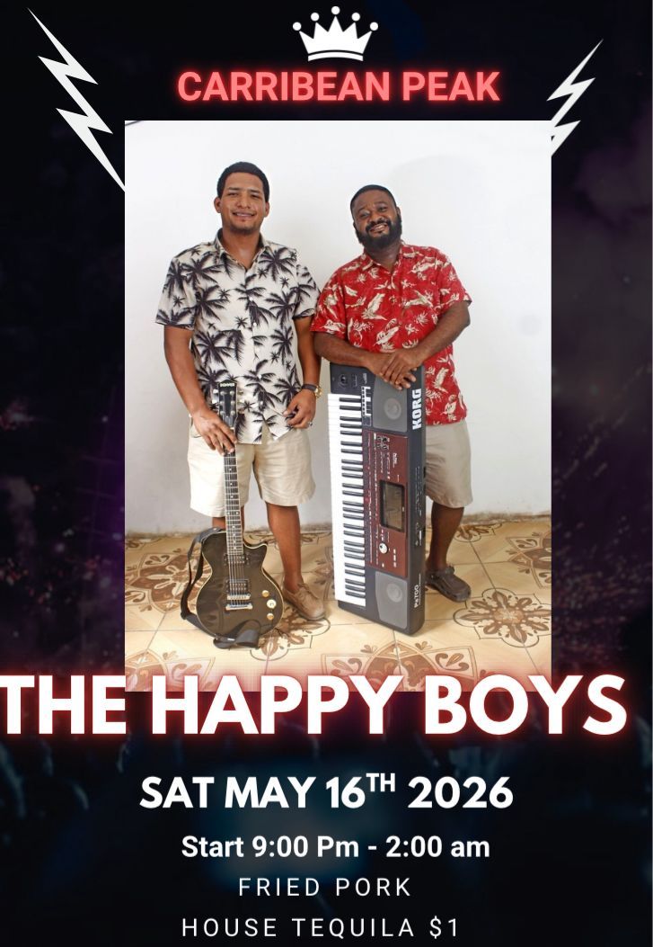 Two musicians from Roatan, Honduras, pose with a guitar and keyboard at a Caribbean-themed event, standing against a plain white wall.